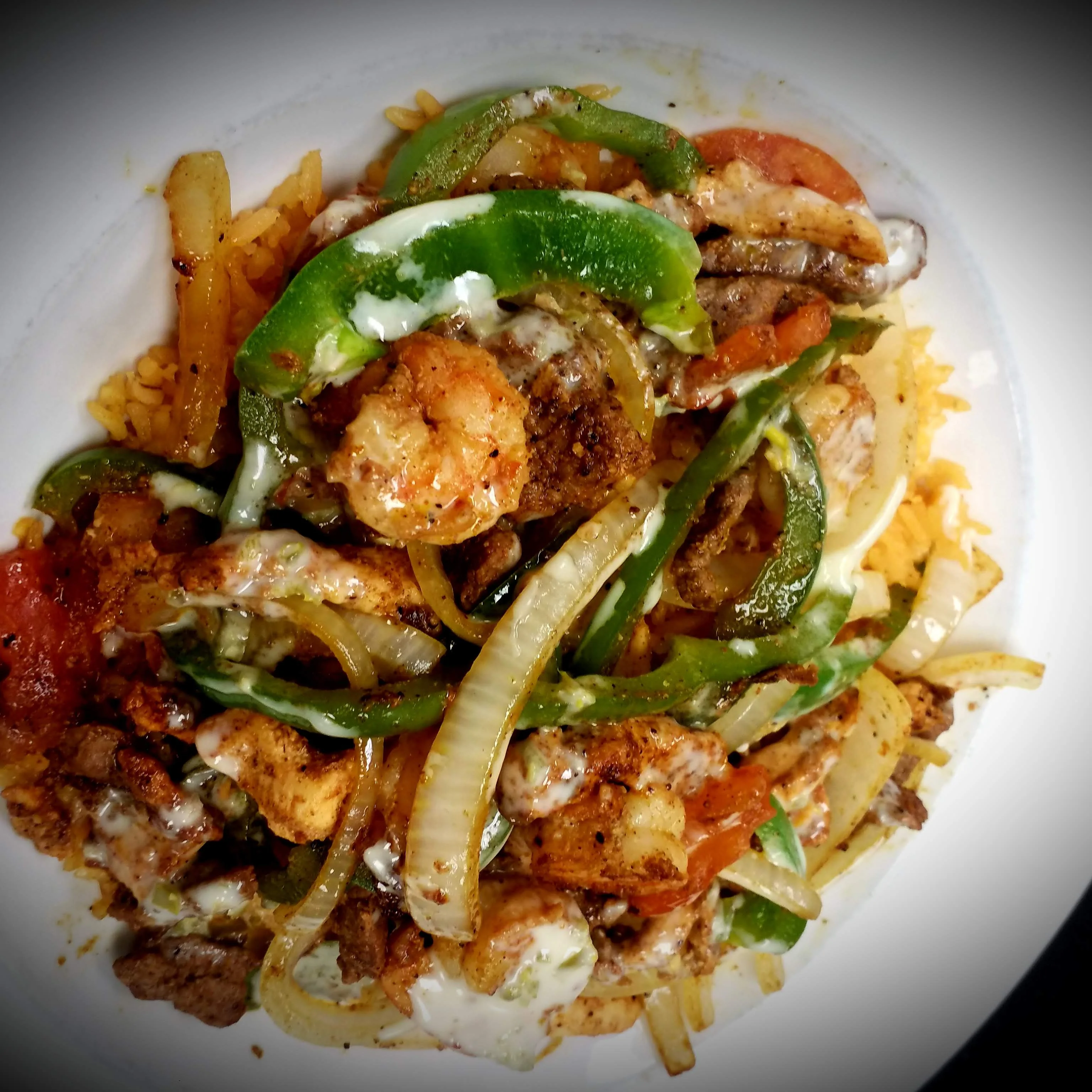 Best Arroz Texano/ Texas Rice in Radford Virginia served with seasoned rice topped with chicken, beef, shrimp, sautéed bell peppers, onions, tomatoes, and drizzled with melted cheese.