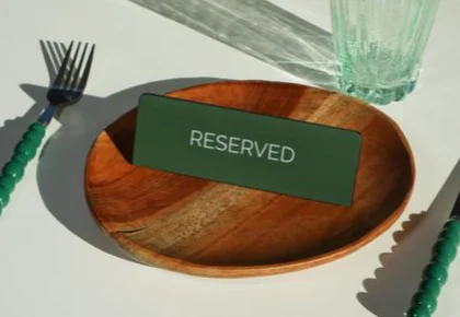 Reserved table setting with wooden plate and green sign