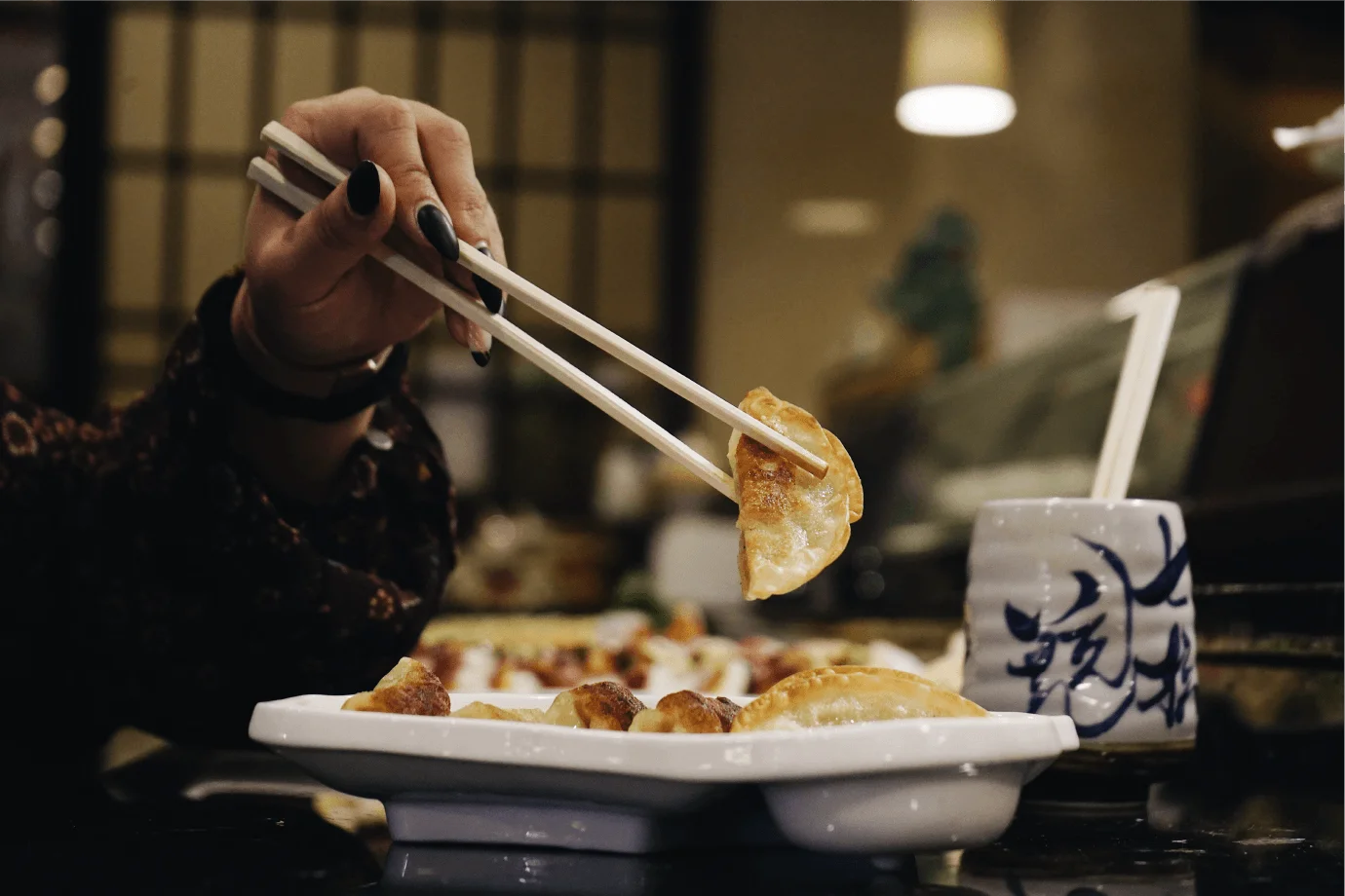 Guest picking up a gyoza with chopsticks at Mahzu East Windsor