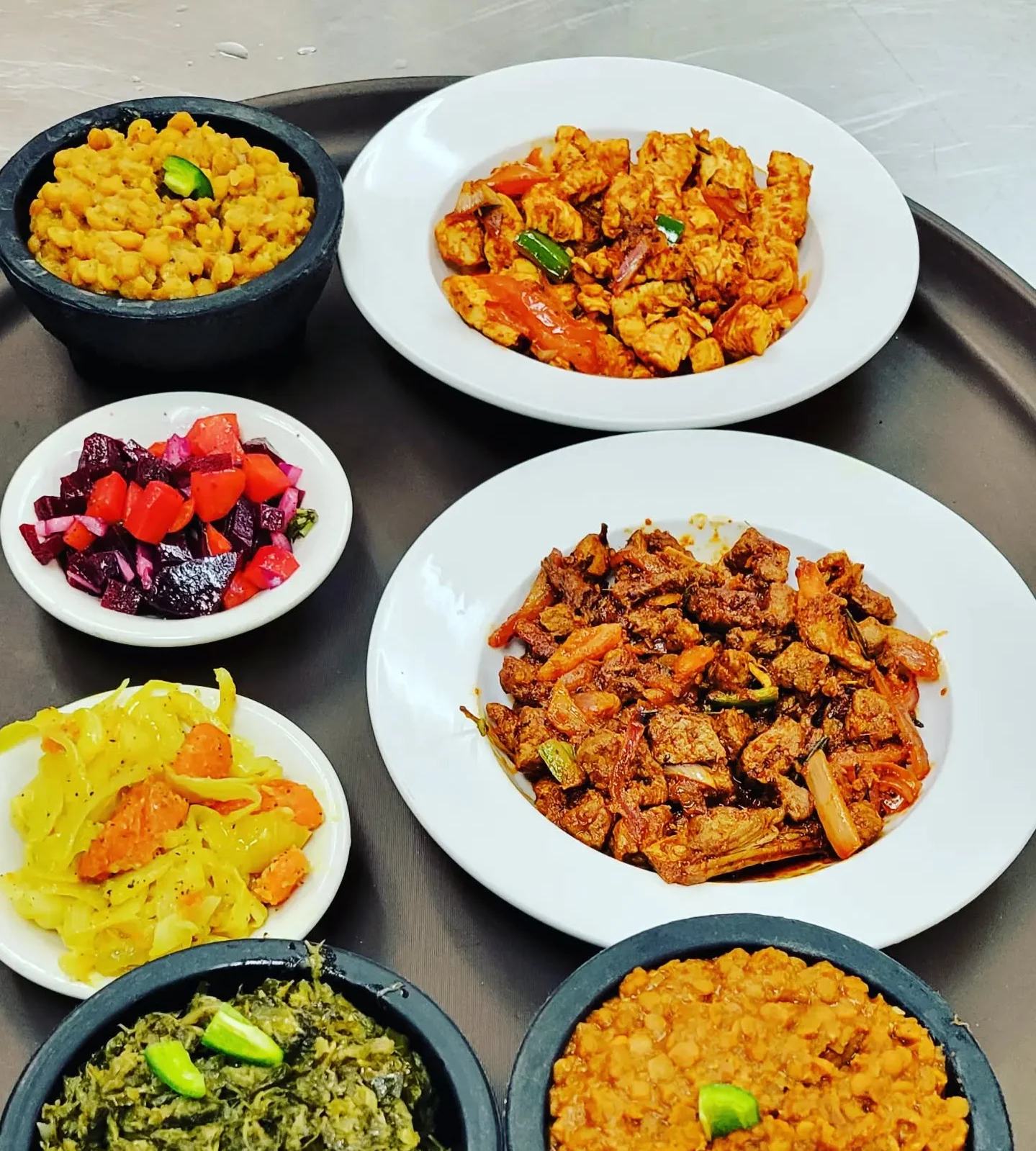 A dish of green beans and carrots stir-fried together, accompanied by flatbreads on a metal tray.