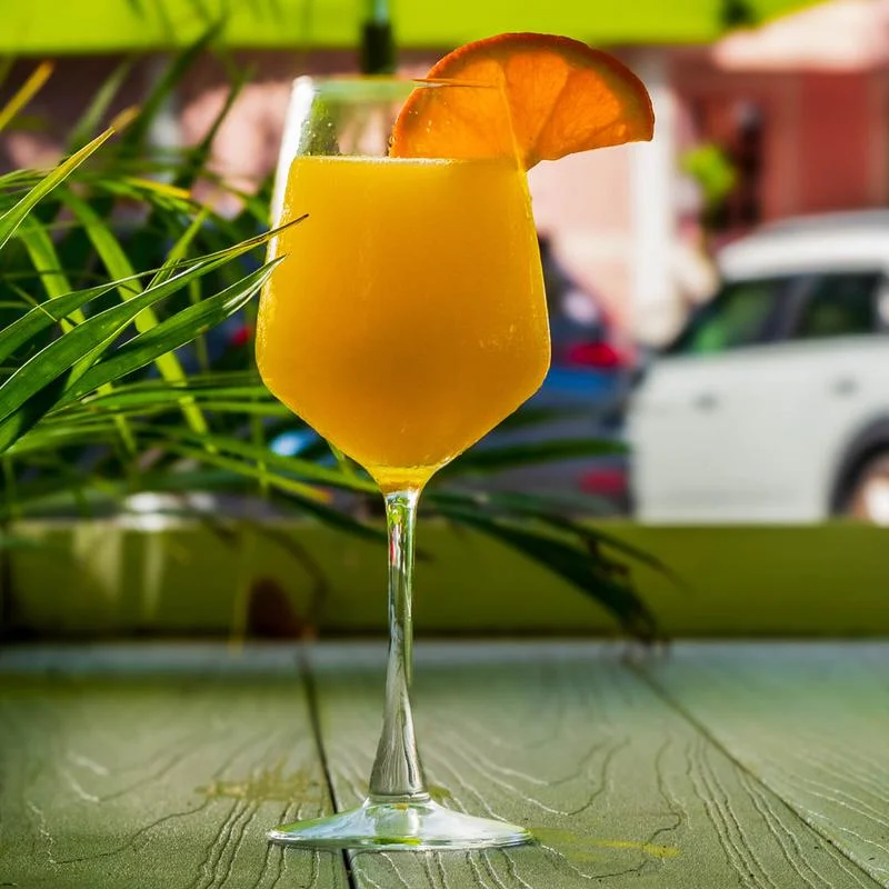 Tropical orange cocktail in a wine glass with citrus garnish