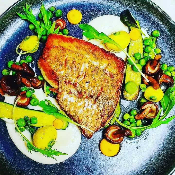 Pan-seared fish with seasonal vegetables on a modern plate