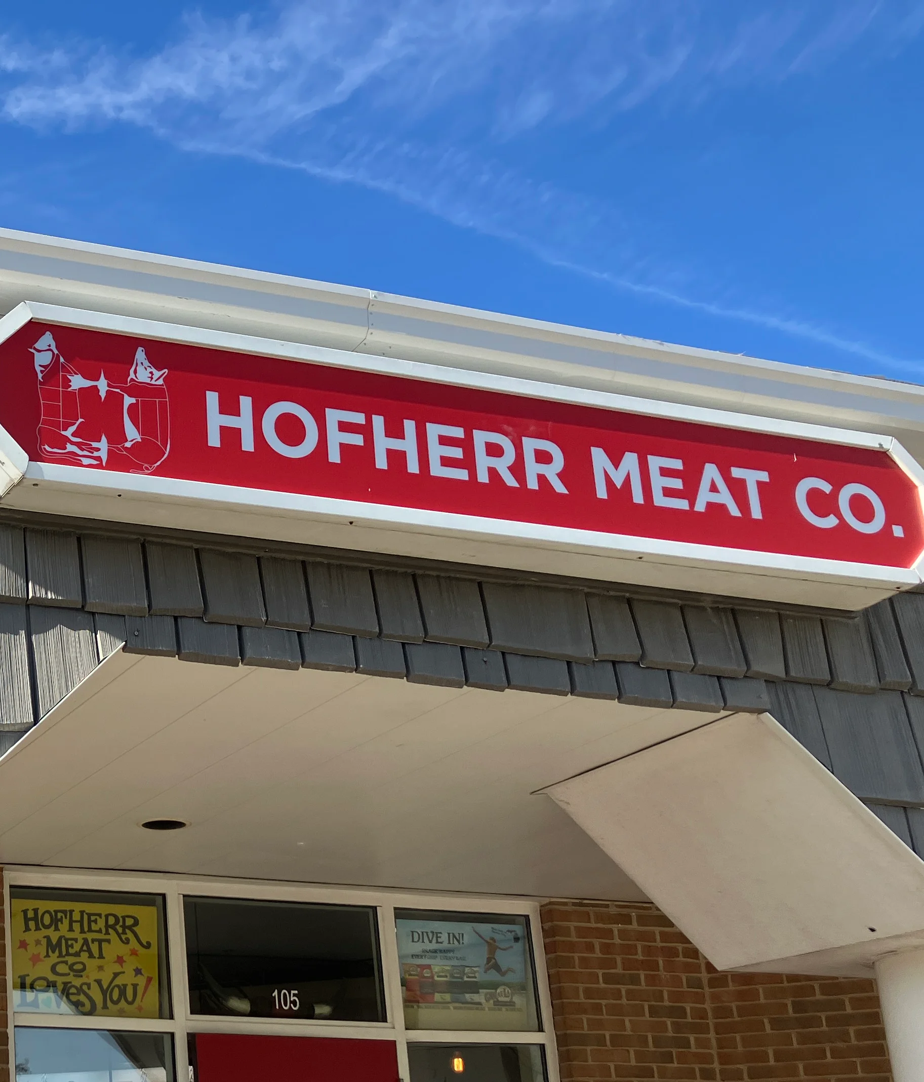 Exterior of Hofherr Meat Co. with American flag and welcoming storefront