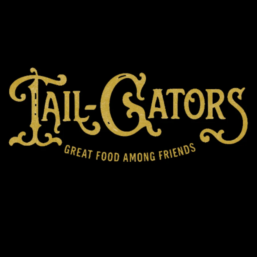 A decorative logo featuring the name 'Tail-Gators' with a tagline 'Great Food Among Friends.' The text is stylized in golden tones.