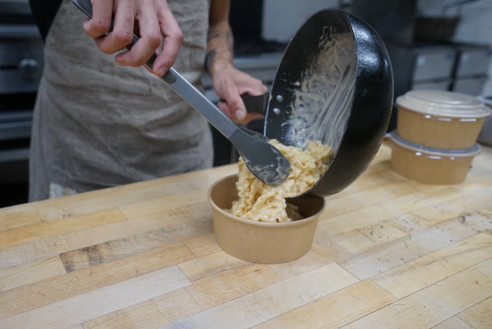 Creamy mac and cheese being served in a takeout container
