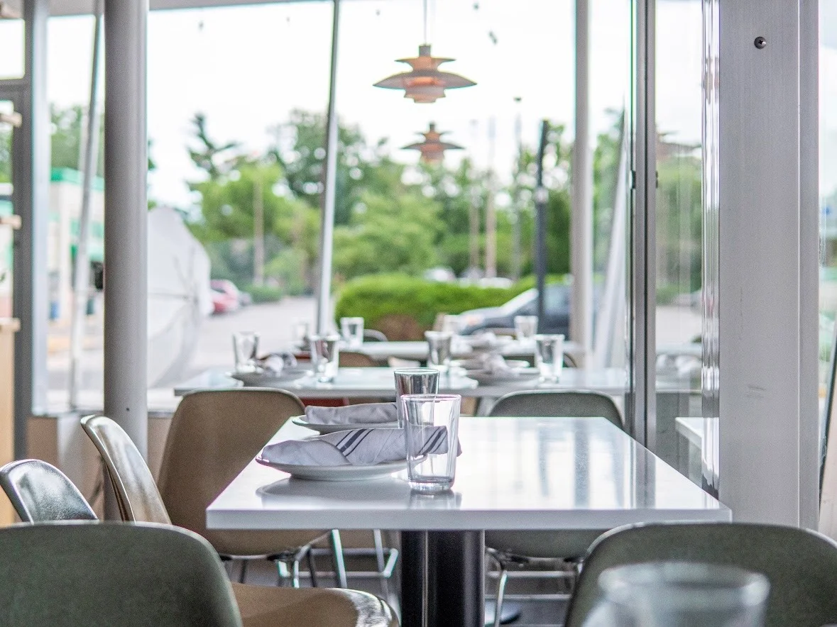 A neatly arranged restaurant counter featuring a stack of folded napkins on a small dish. The background is blurred with ambient lighting creating a warm atmosphere.