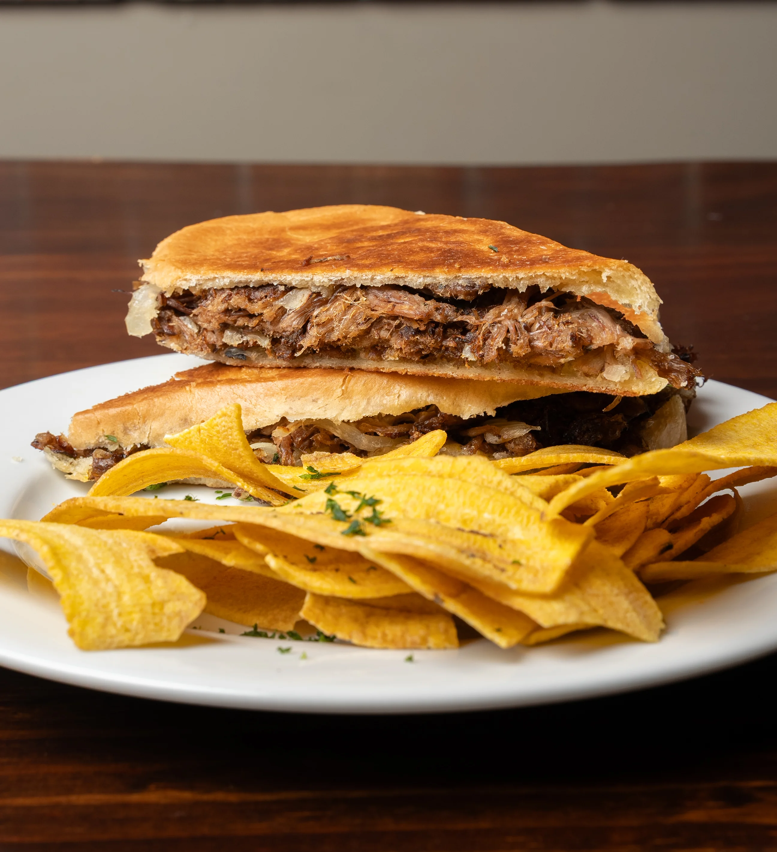 Cuban sandwich with crispy plantain chips on a white plate