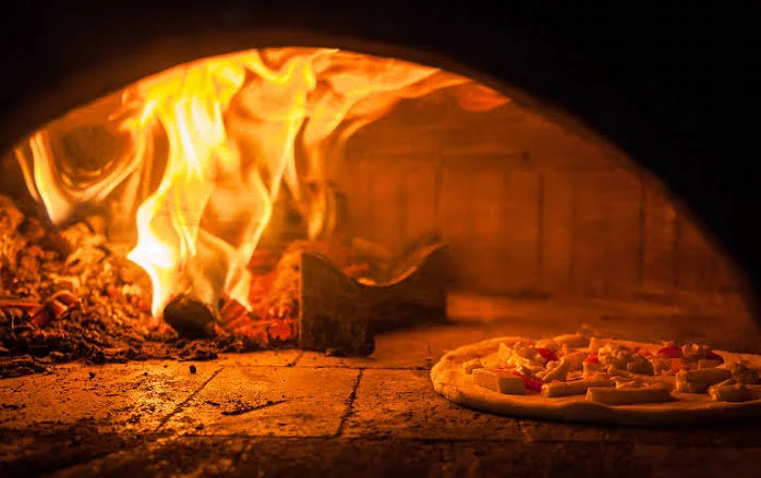 Wood-fired Margherita pizza baking in a traditional oven