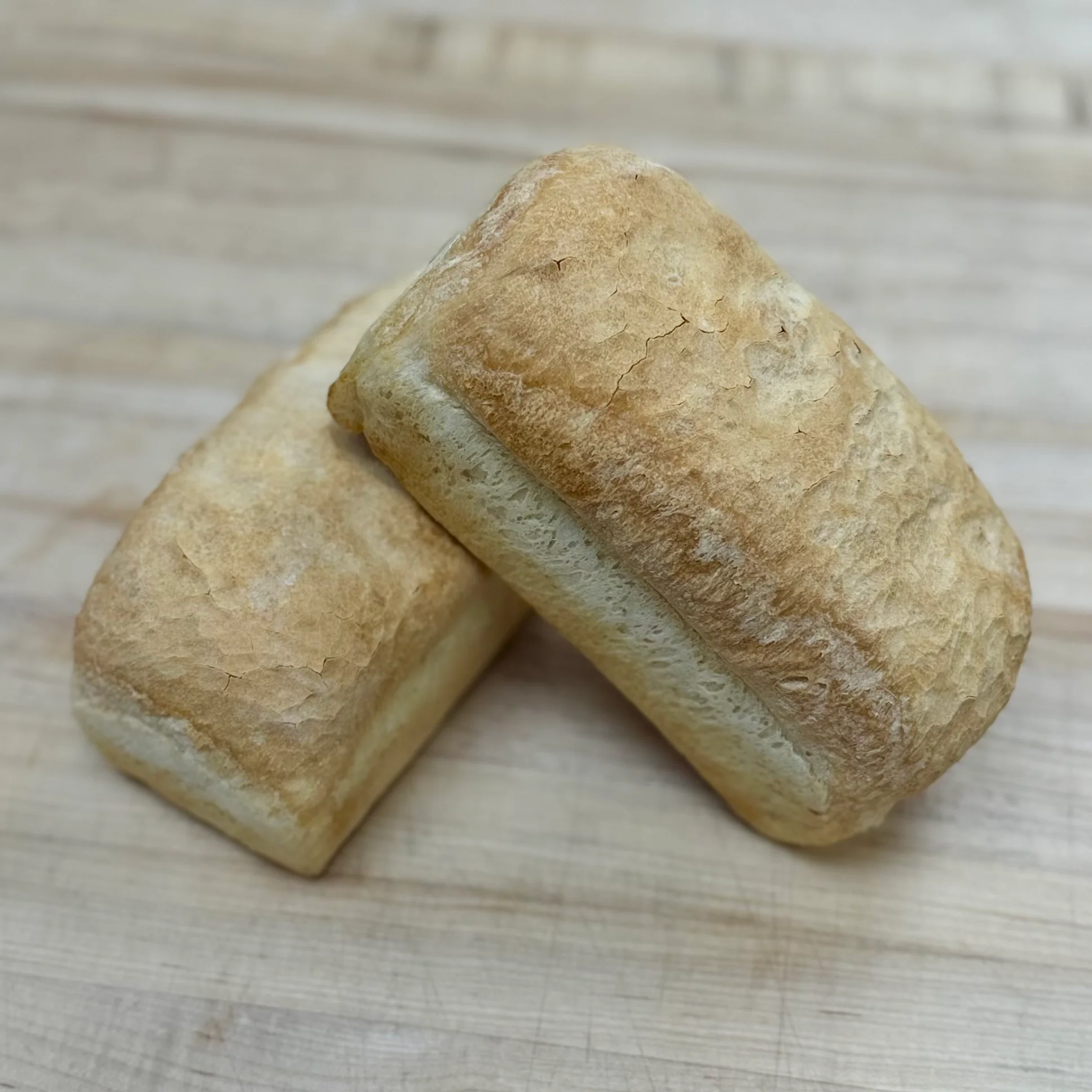 Freshly baked Italian ciabatta loaves on a wooden surface