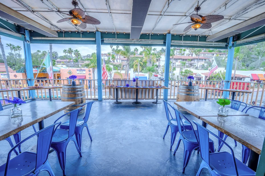 Cozy restaurant patio with blue chairs and palm trees