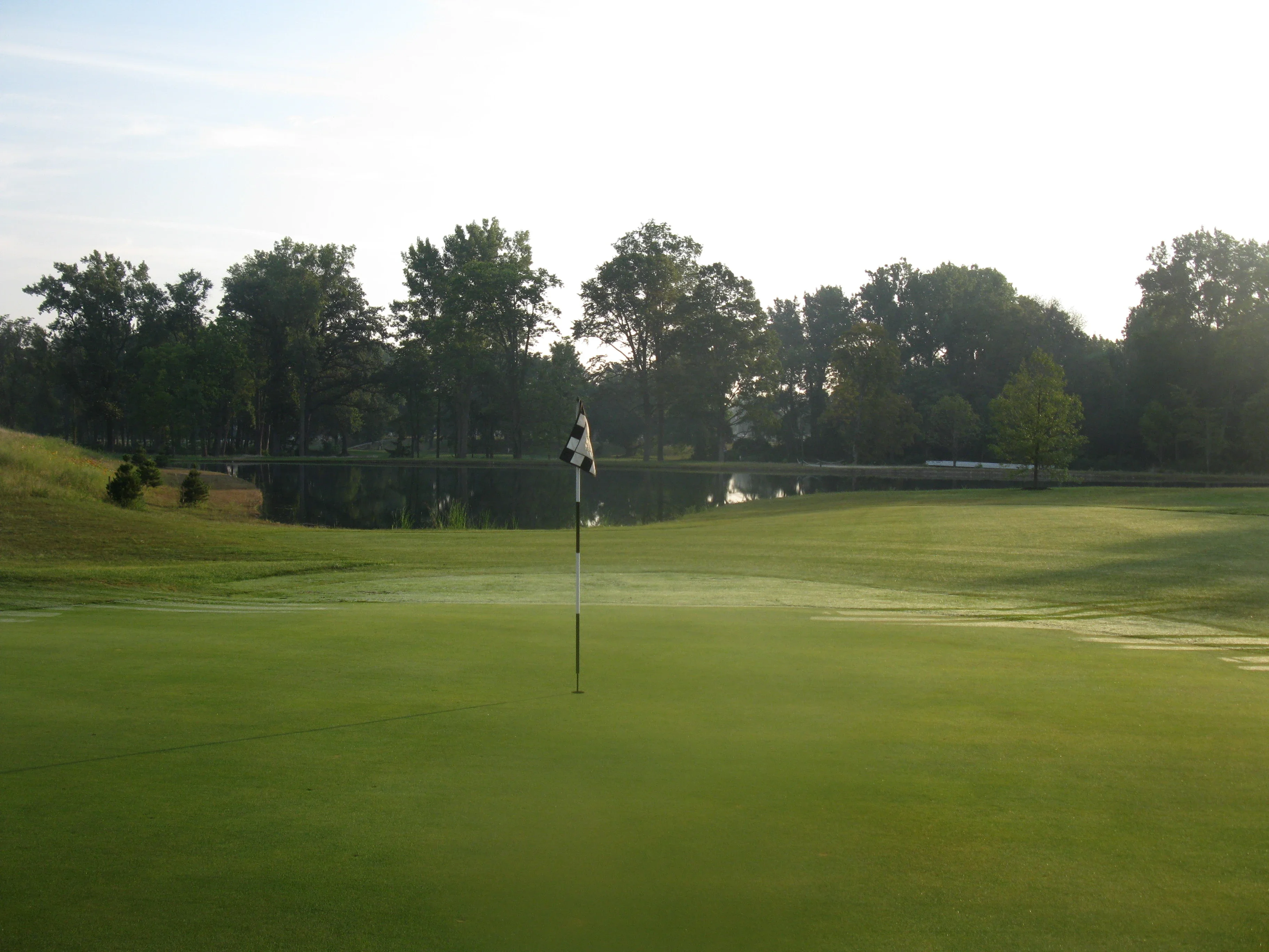 Tranquil golf course view with a flag and pond