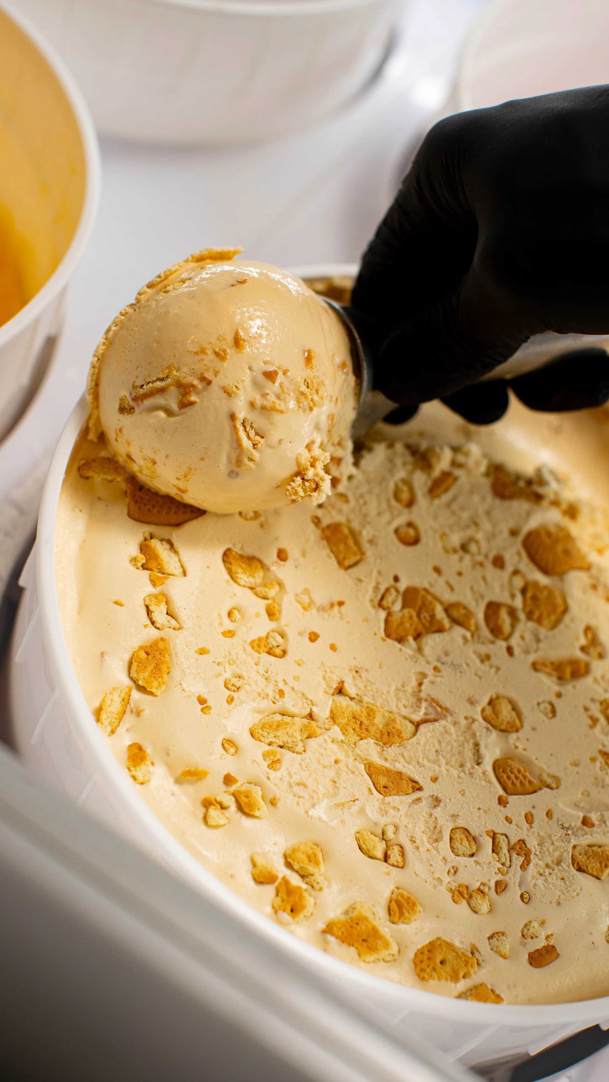 Scoop of creamy ice cream with cookie pieces being served.