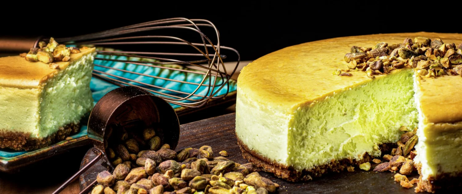 Pistachio cheesecake with a slice cut out, garnished with pistachios.