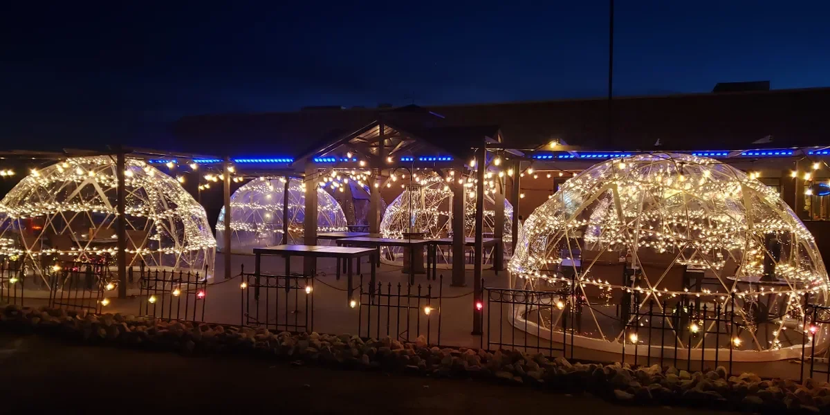 Outdoor dining igloos adorned with fairy lights at night