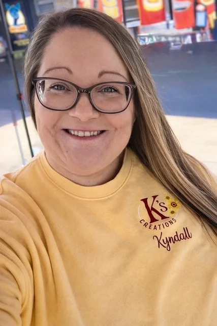 Smiling woman in a yellow sweatshirt at a food stall