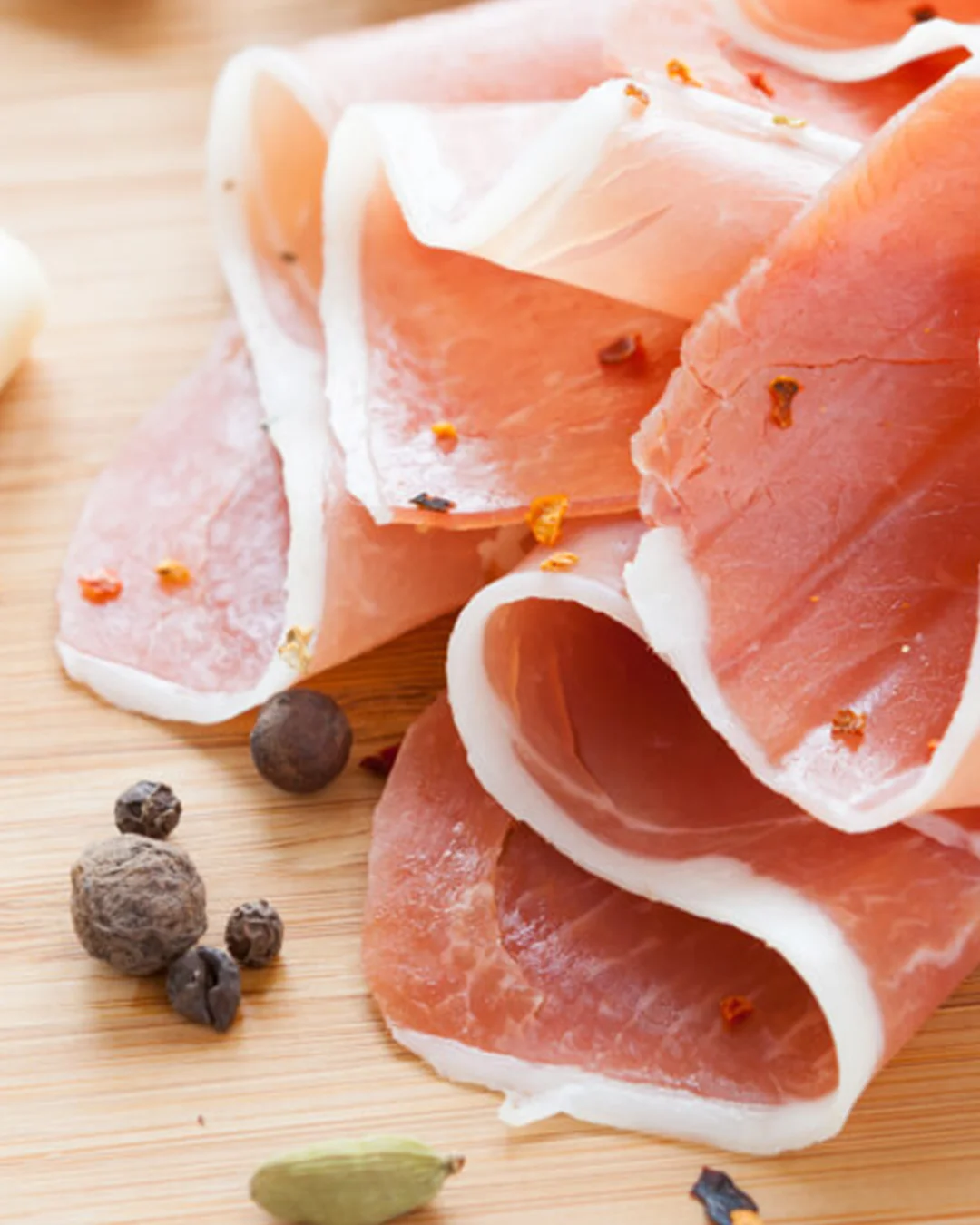 Italian prosciutto on a wooden board with spices
