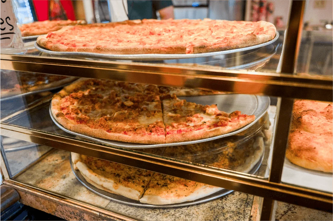 Assorted pizza slices in a display case