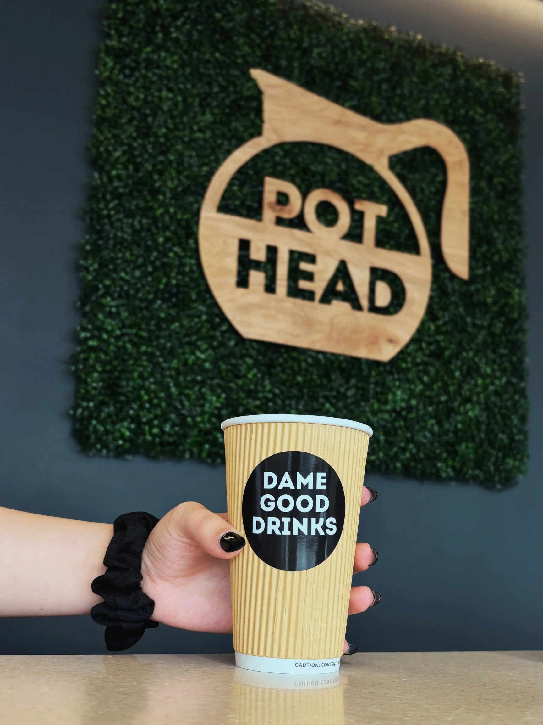 Coffee cup with 'DAME GOOD DRINKS' at Pot Head cafe