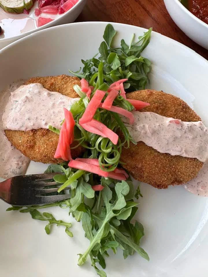Crispy fried fish with creamy sauce and fresh greens