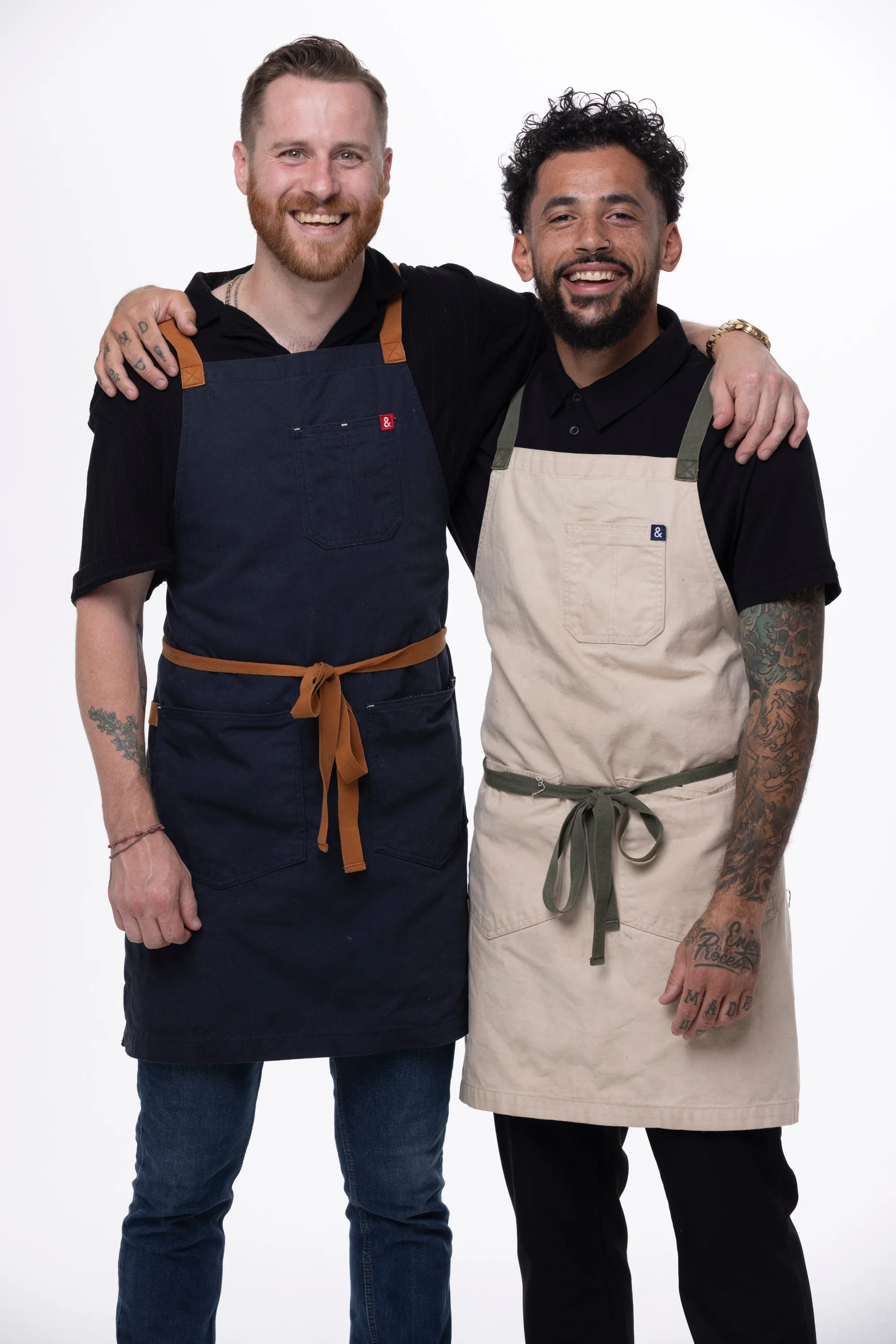 Three chefs in aprons smiling together in a studio setting