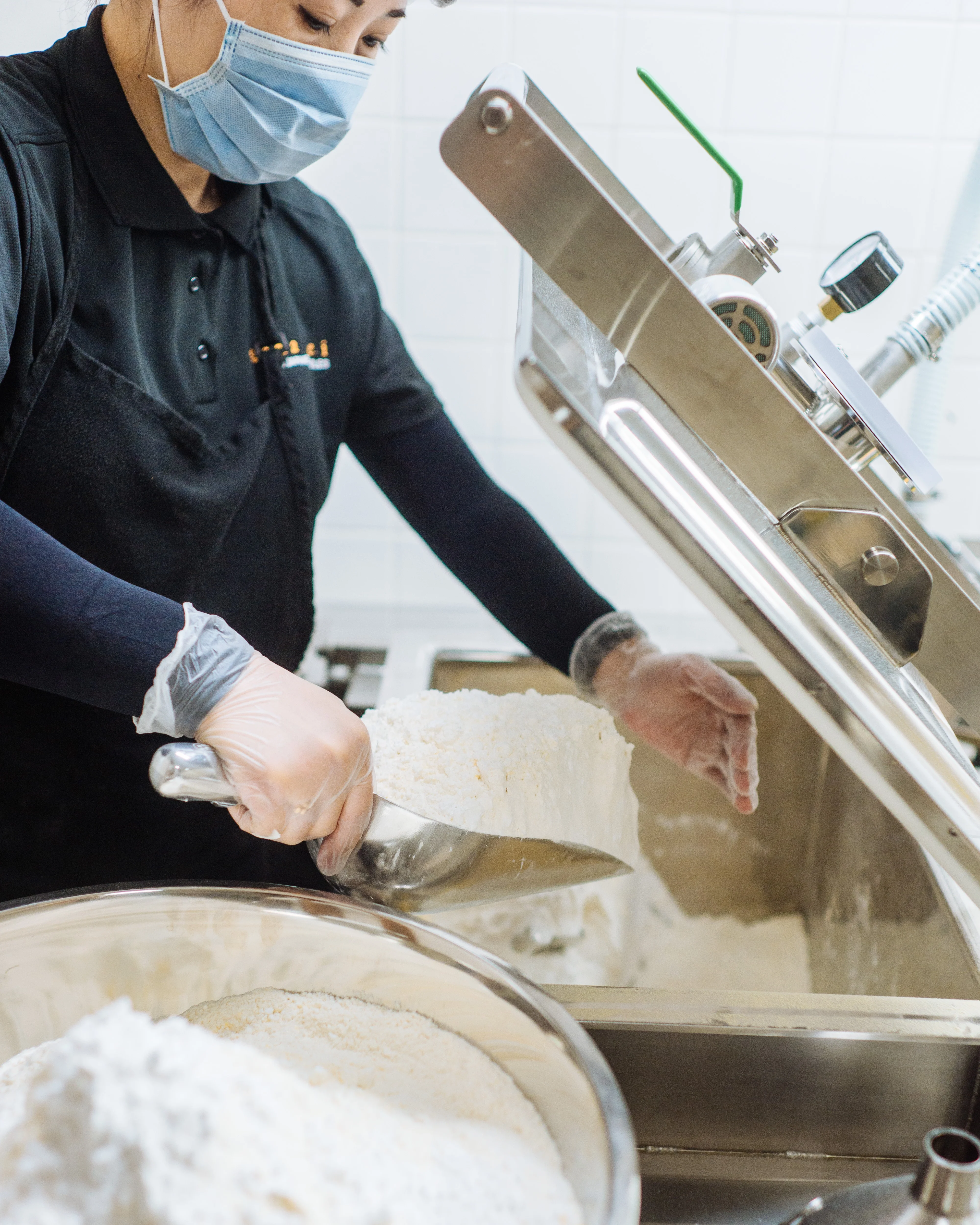 Goma Tei team member adding flour during the fresh noodle-making process.