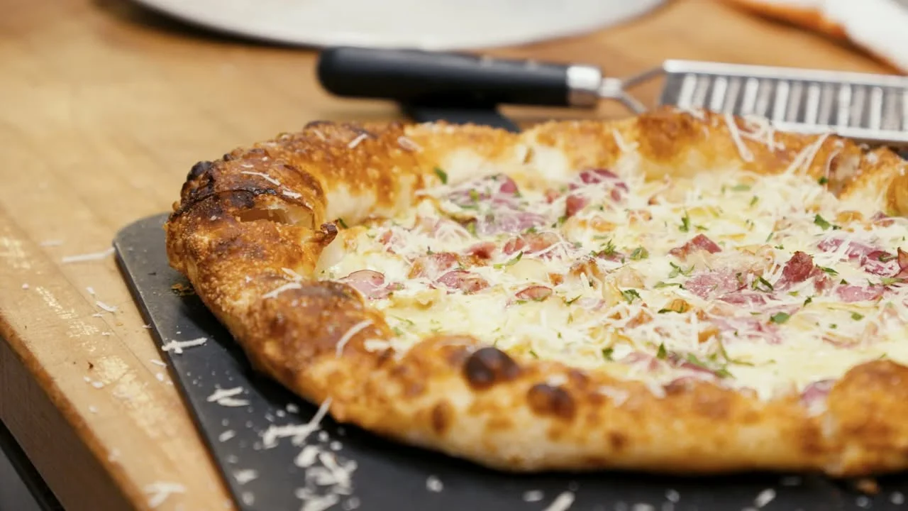 A pizza topped with cheese and meat, featuring a thick, crispy crust and sprinkled with herbs.