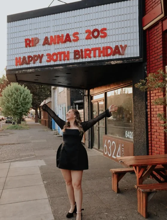 Woman celebrating 30th birthday in front of a marquee sign.