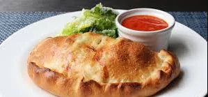 Golden calzone served with marinara sauce and fresh greens