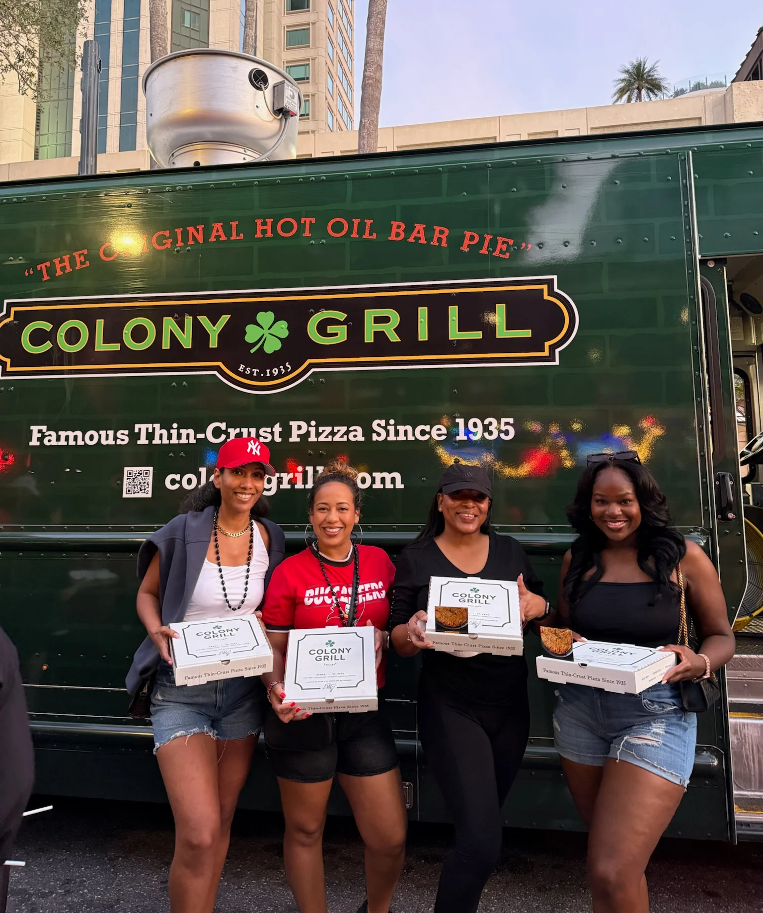 Group of friends enjoying Colony Grill pizza from a food truck