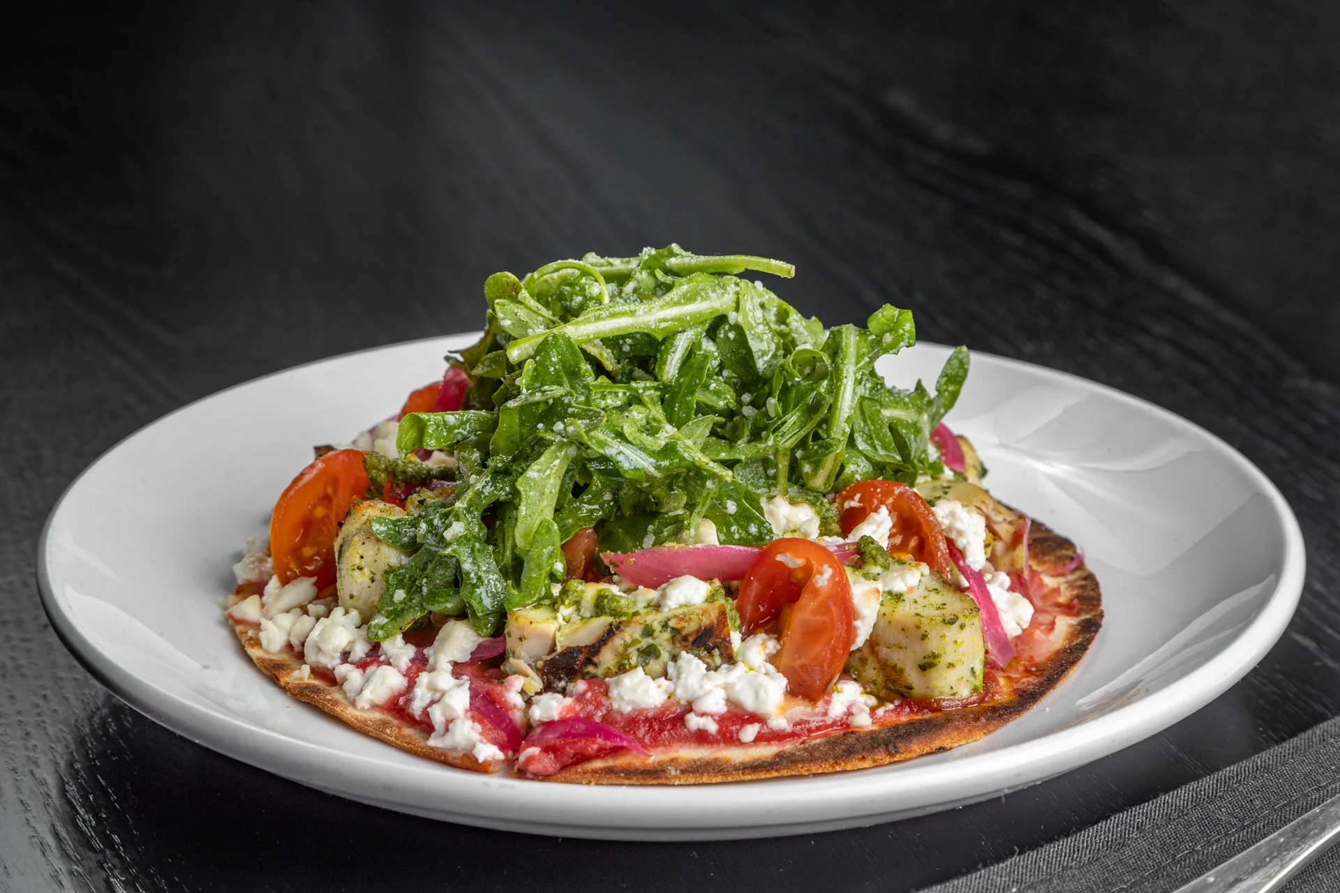 Mediterranean flatbread topped with fresh greens and tomatoes