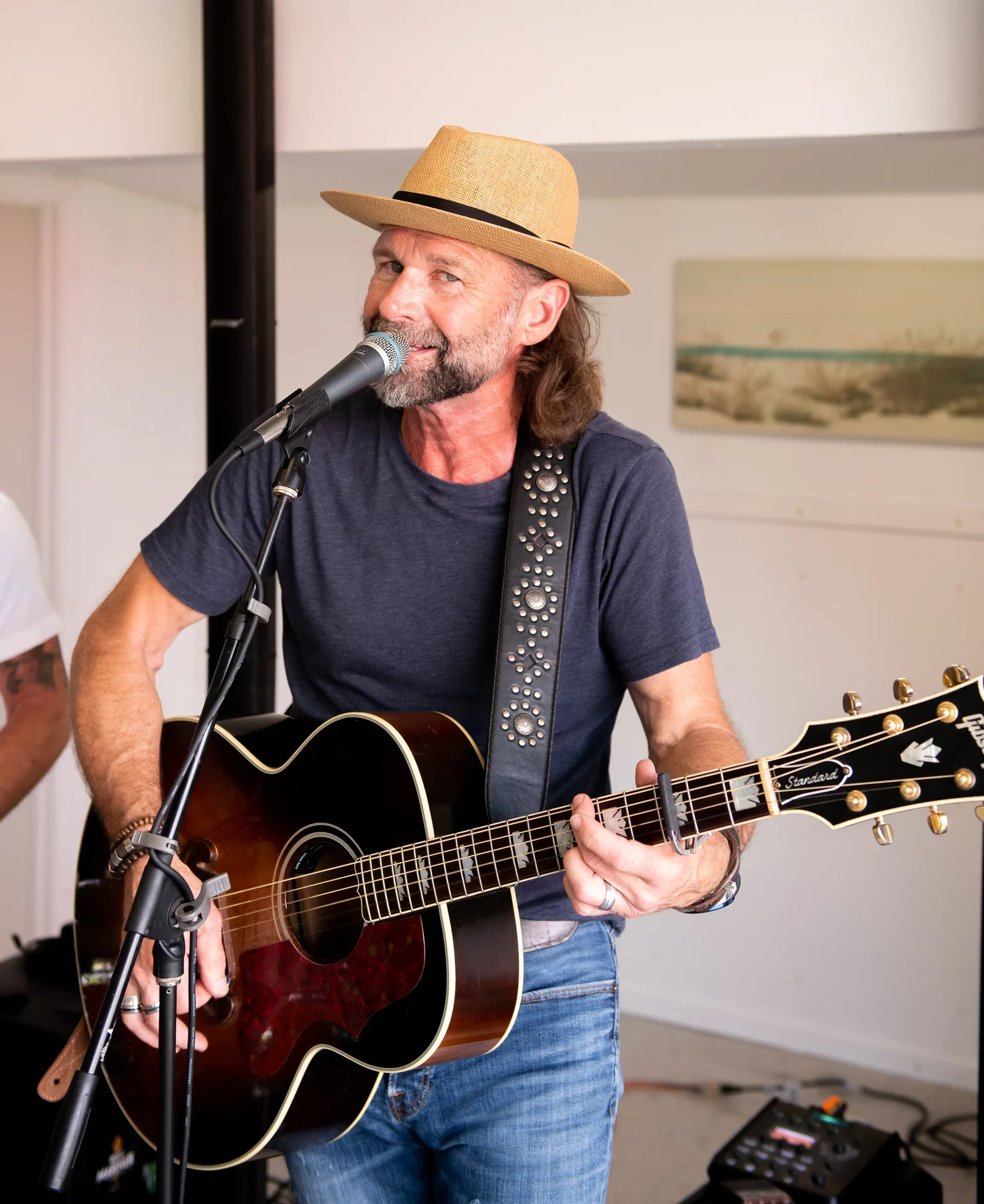 Musician performing live with acoustic guitar and microphone