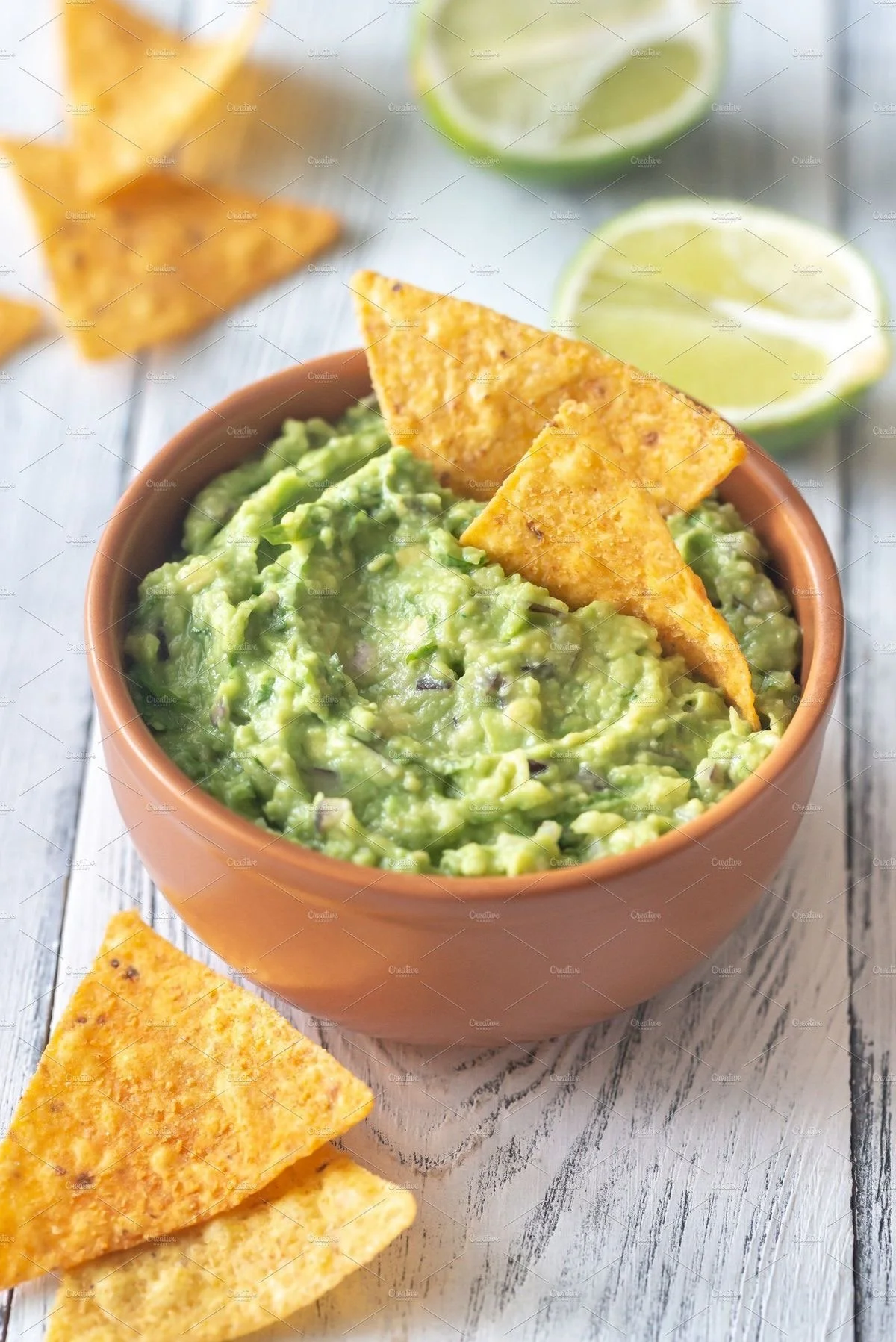 Bowl of guacamole with tortilla chips and lime wedges