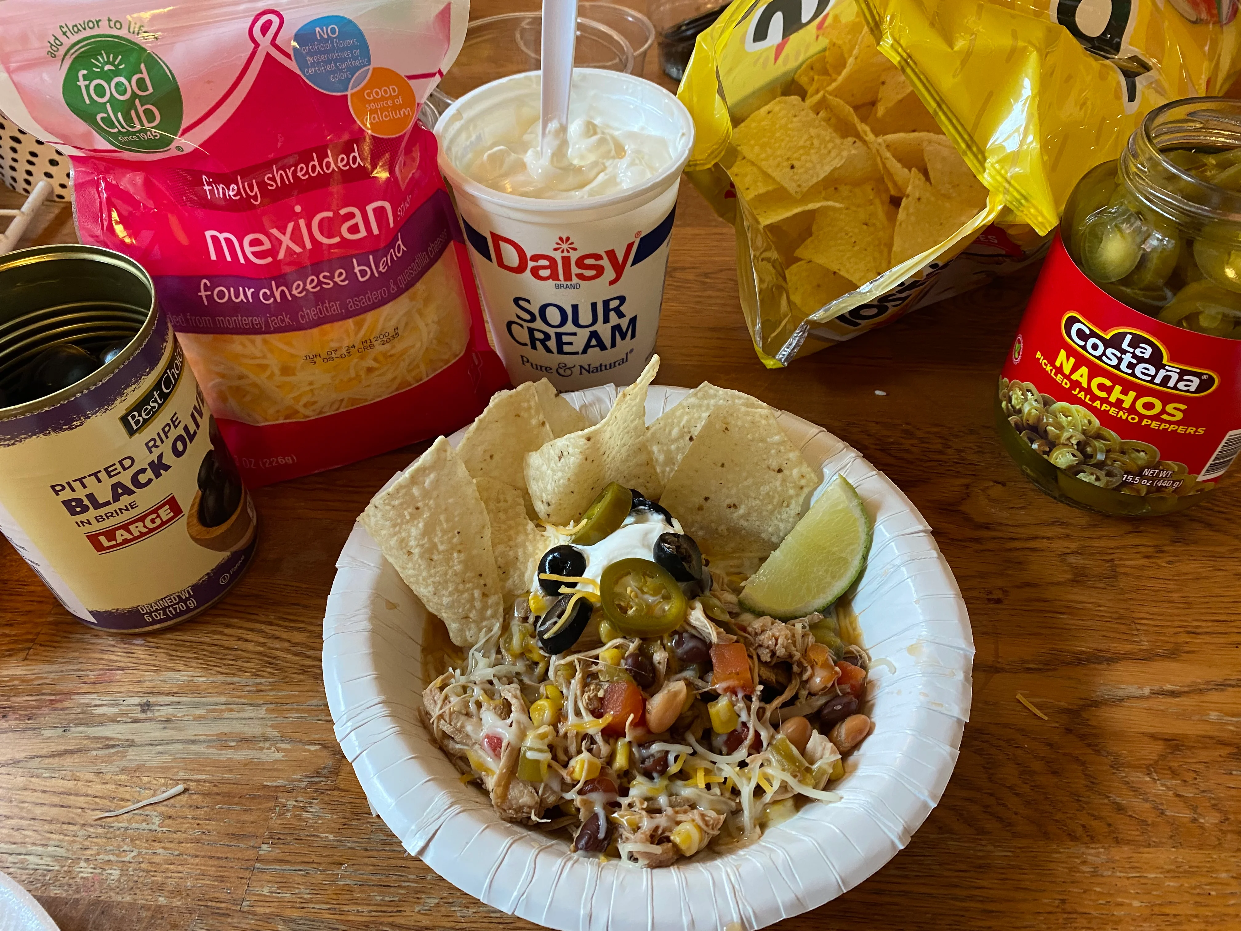 Bowl of Mexican chicken nachos with toppings and sides