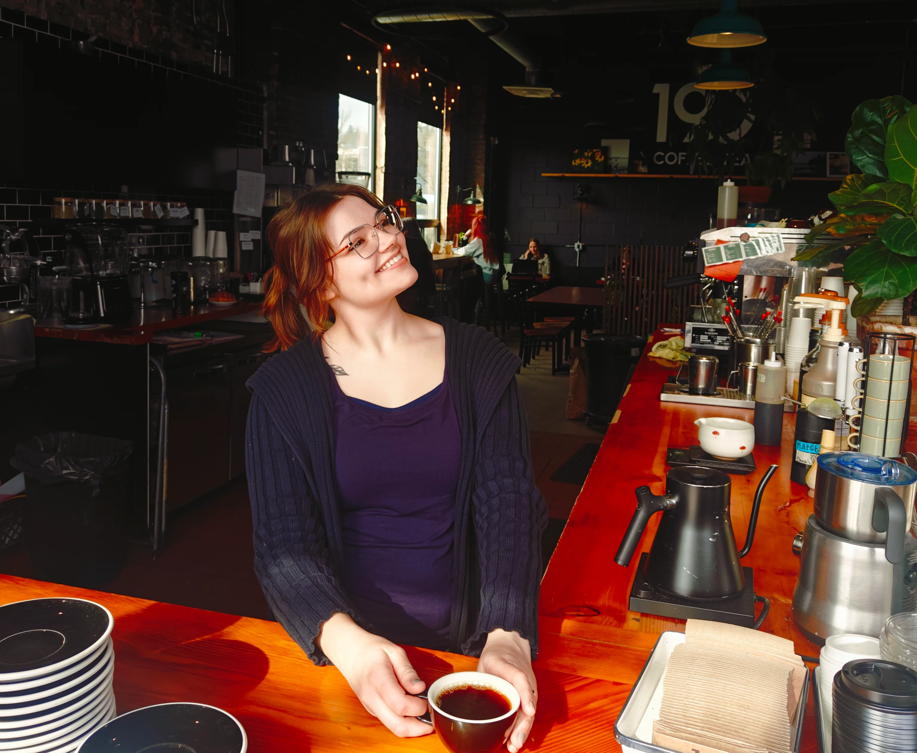 Barista smiling with coffee in a cozy café setting