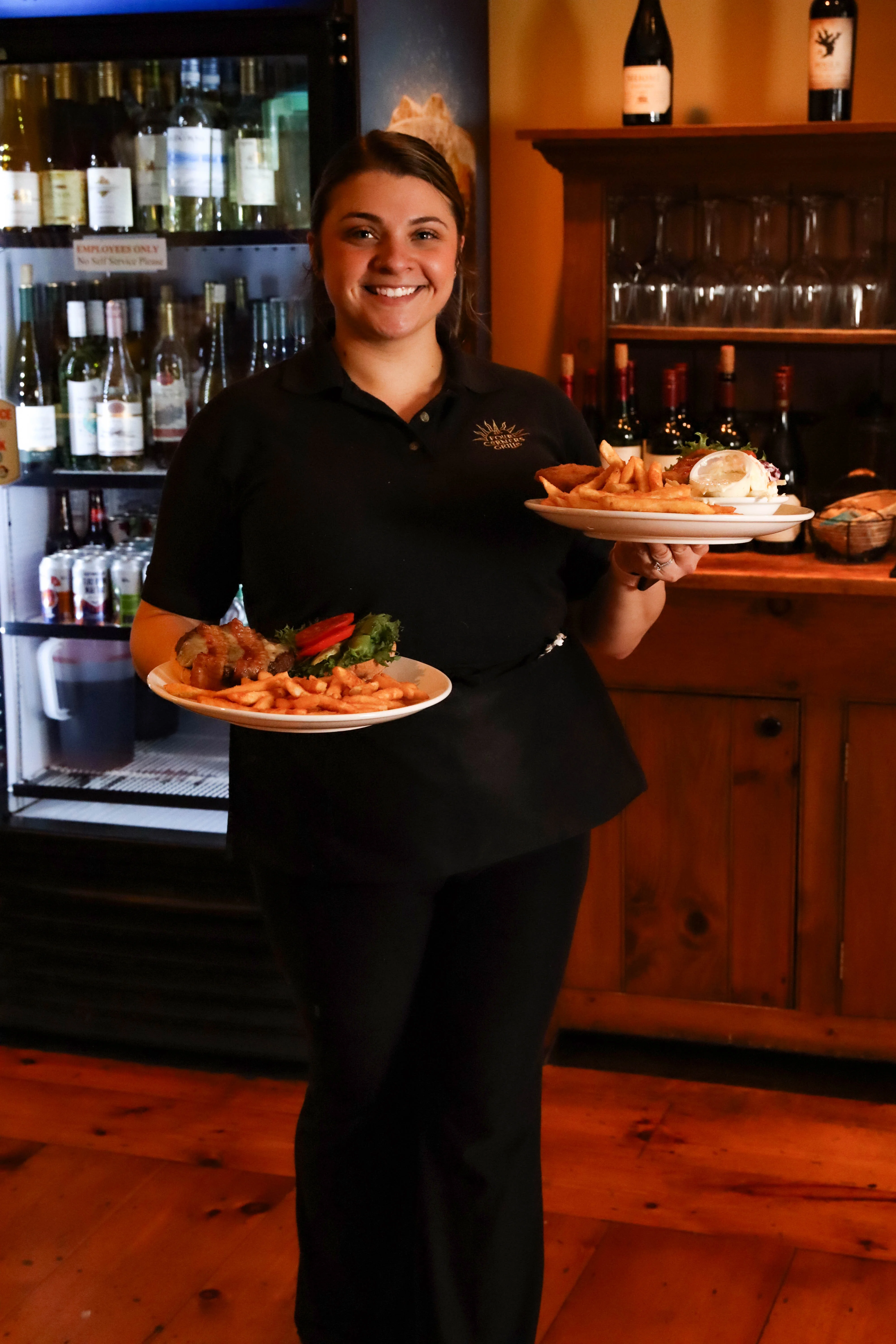Server presenting plates of fried seafood and fries in a cozy restaurant