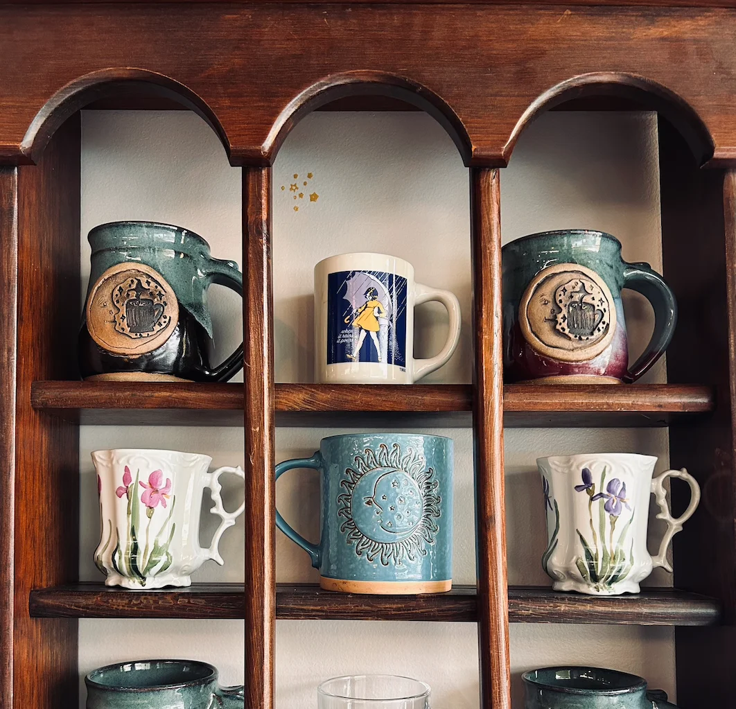 Colorful ceramic mugs displayed on a wooden shelf