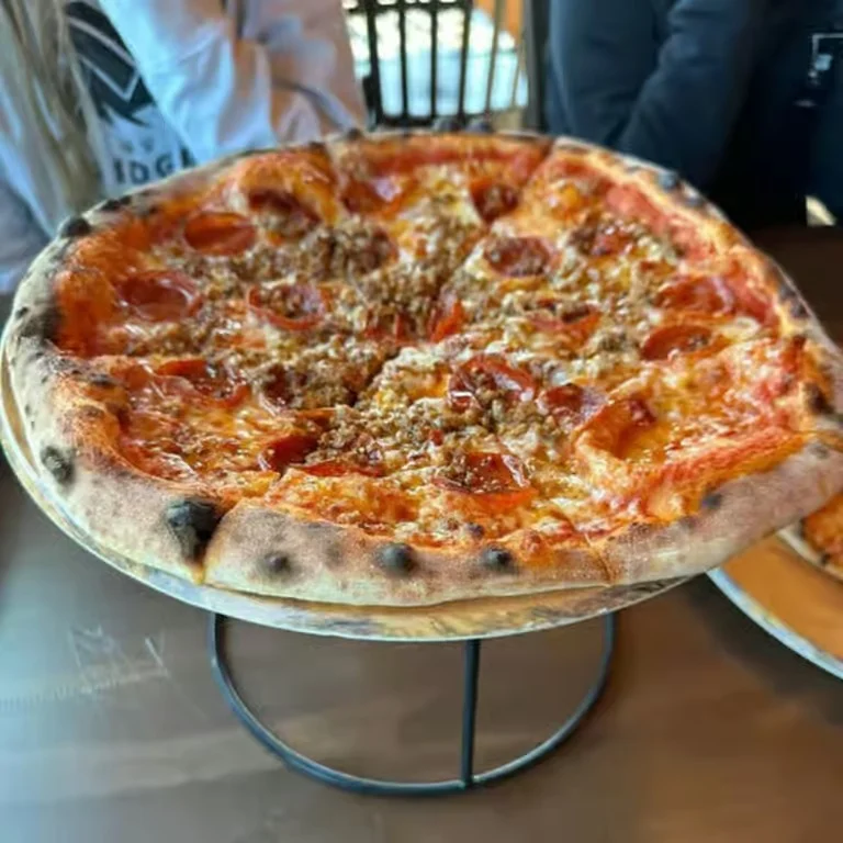 Pepperoni and sausage pizza on a wooden serving stand