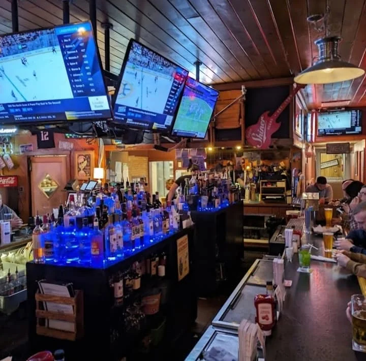 Lively bar scene with multiple TVs and colorful drinks