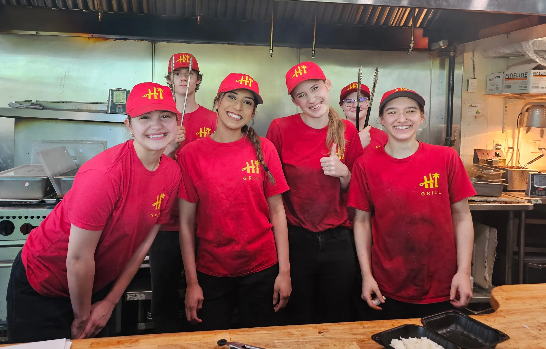 Team of chefs smiling in a busy restaurant kitchen
