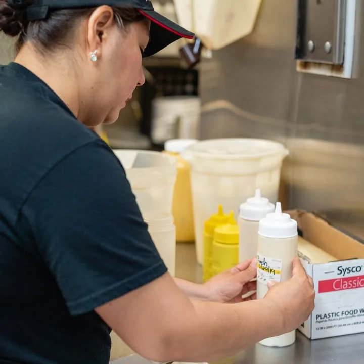 Staff member preparing condiments in a busy restaurant kitchen