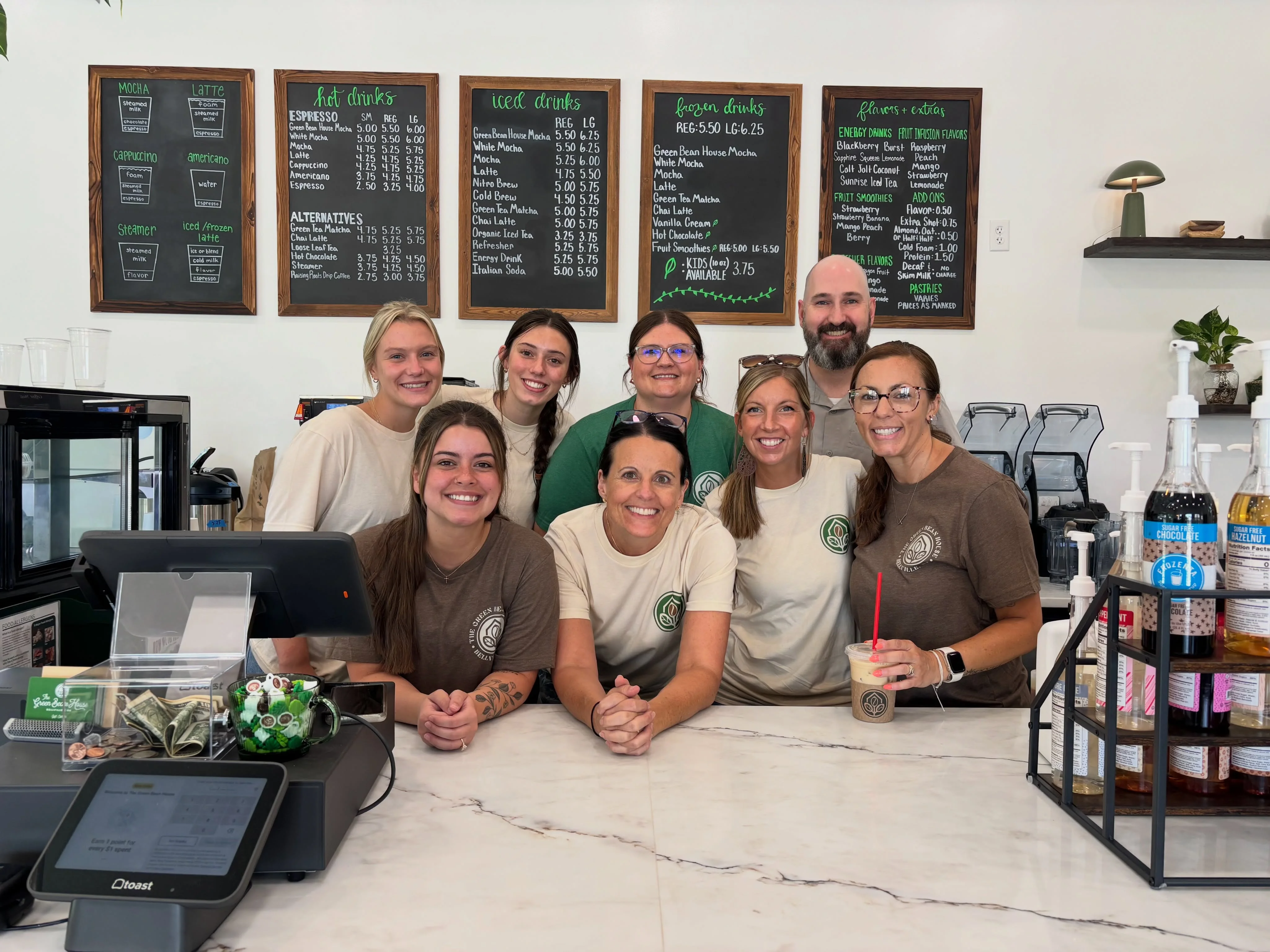 Friendly staff at a coffee shop with menu boards in the background