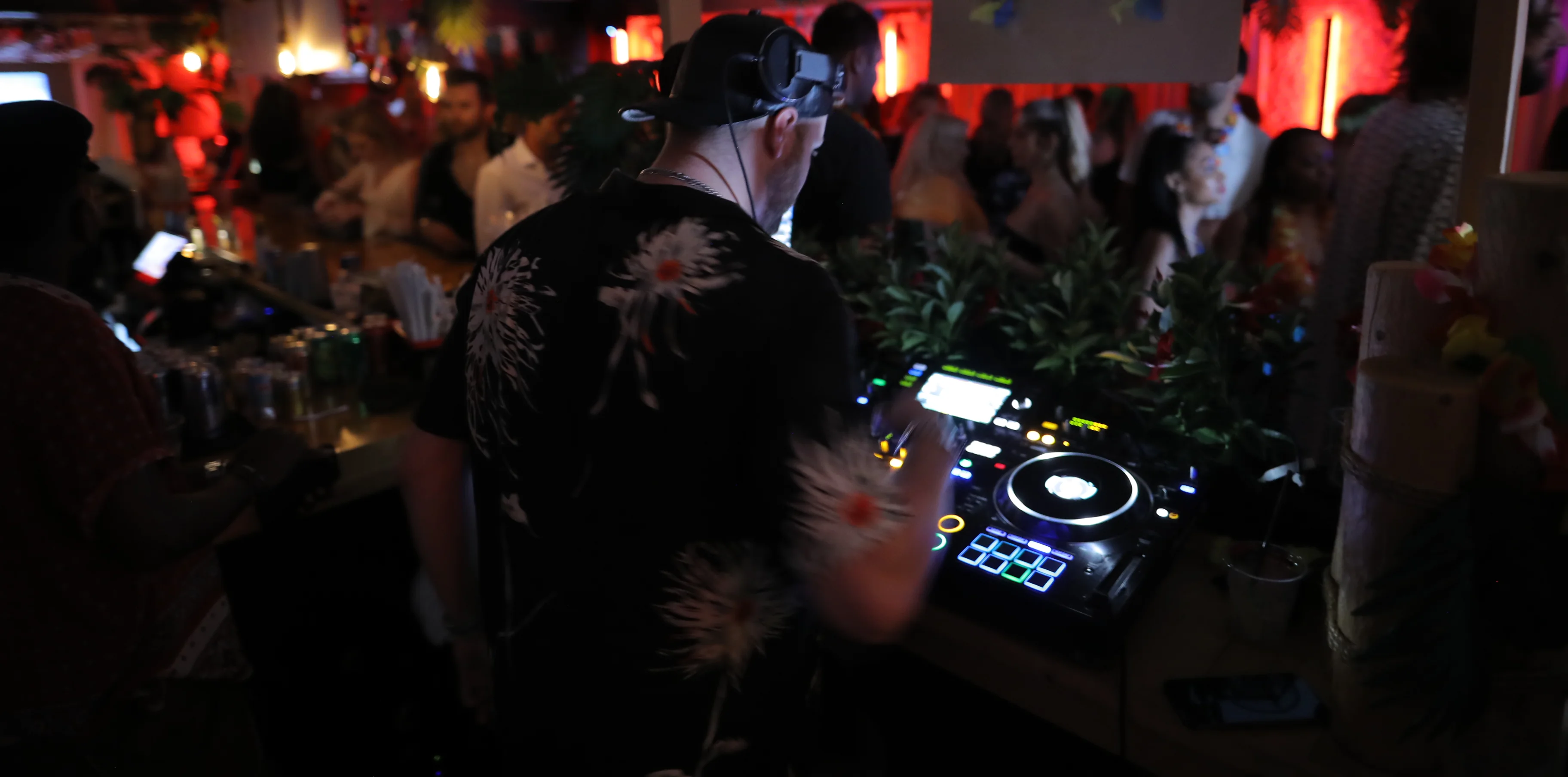 DJ performing at a vibrant bar with tropical decor