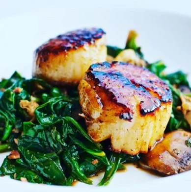 Seared scallops on a bed of sautéed spinach, a classic seafood dish.