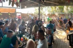 Lively outdoor dining scene with guests enjoying drinks and food