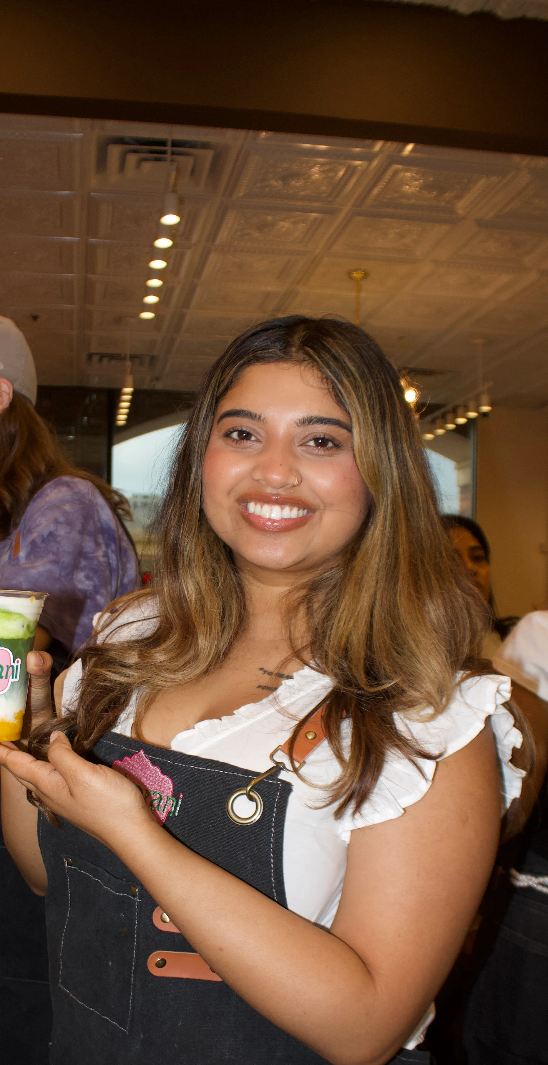 Barista holding a colorful drink at a coffee shop.