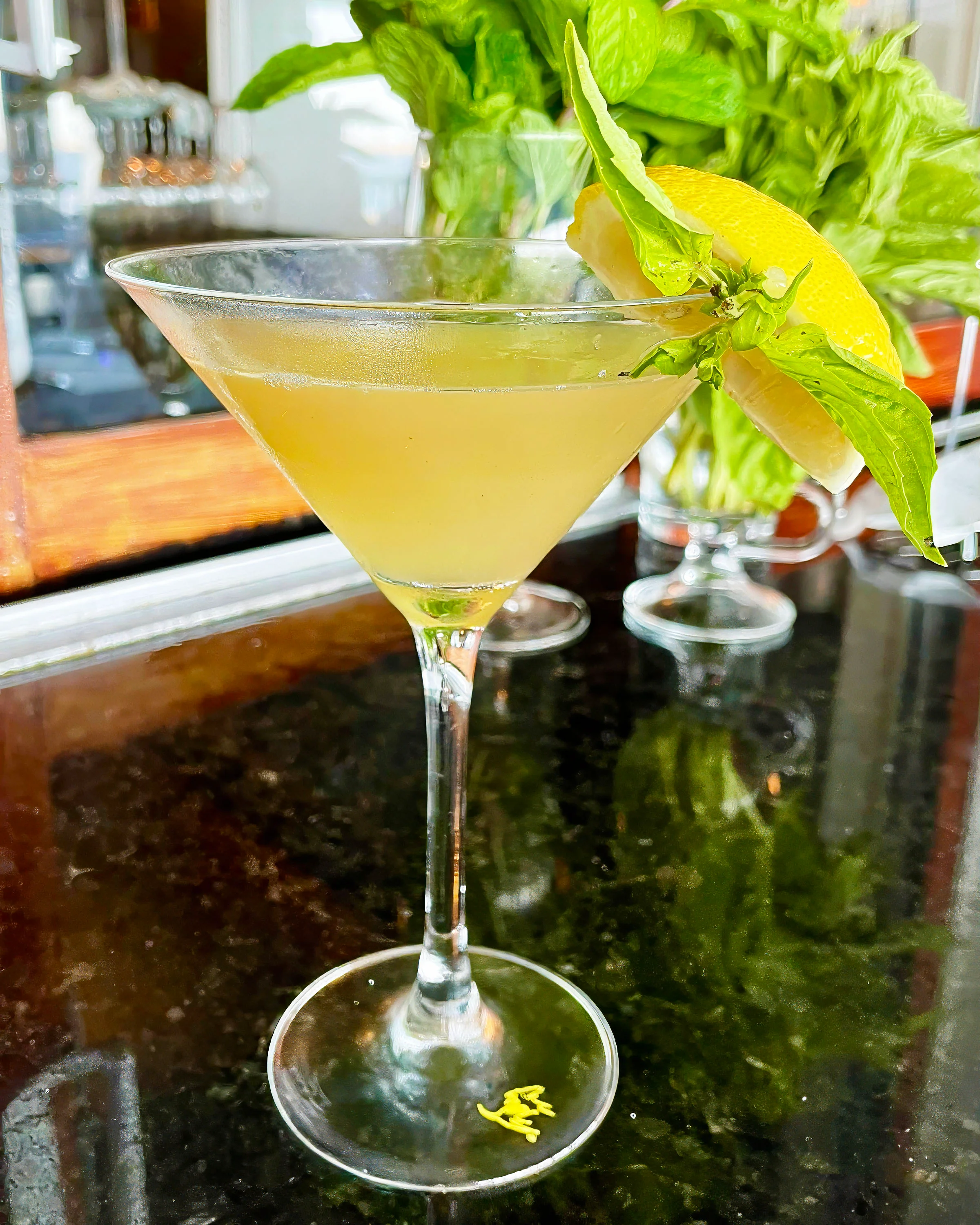 Refreshing cocktail garnished with lemon and basil