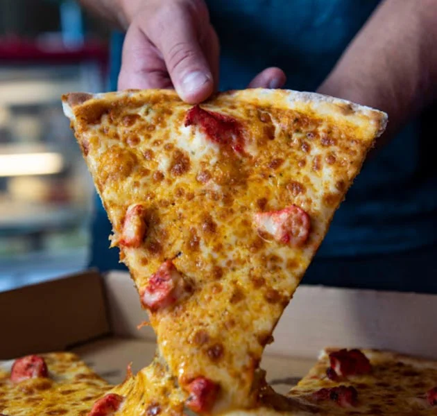 Cheesy pepperoni pizza slice being lifted from the box