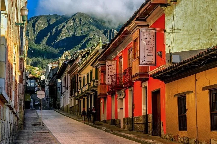 A picturesque street lined with colorful buildings, with mountains in the background.
