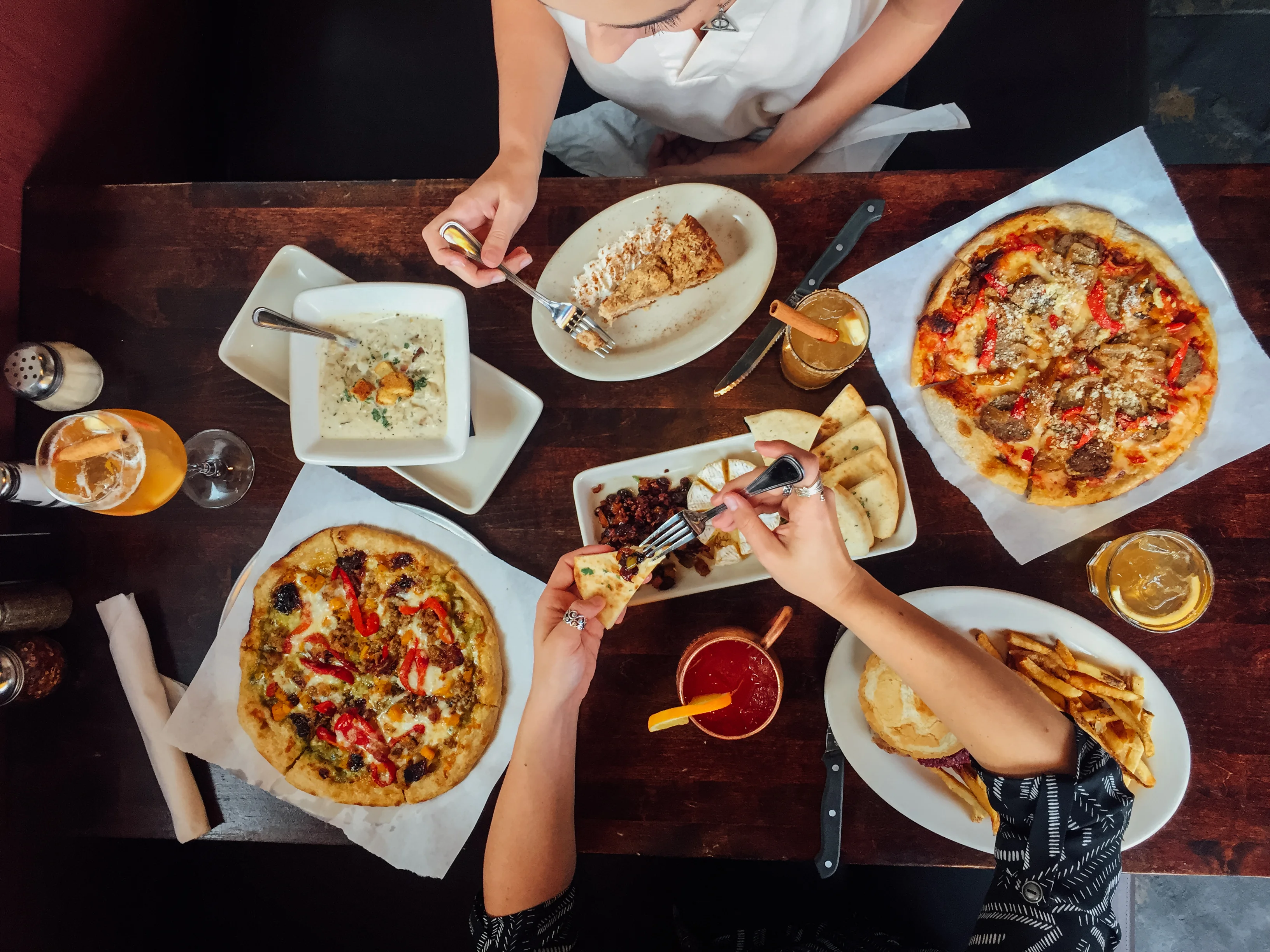 Assorted dishes including pizza and soup on a rustic wooden table