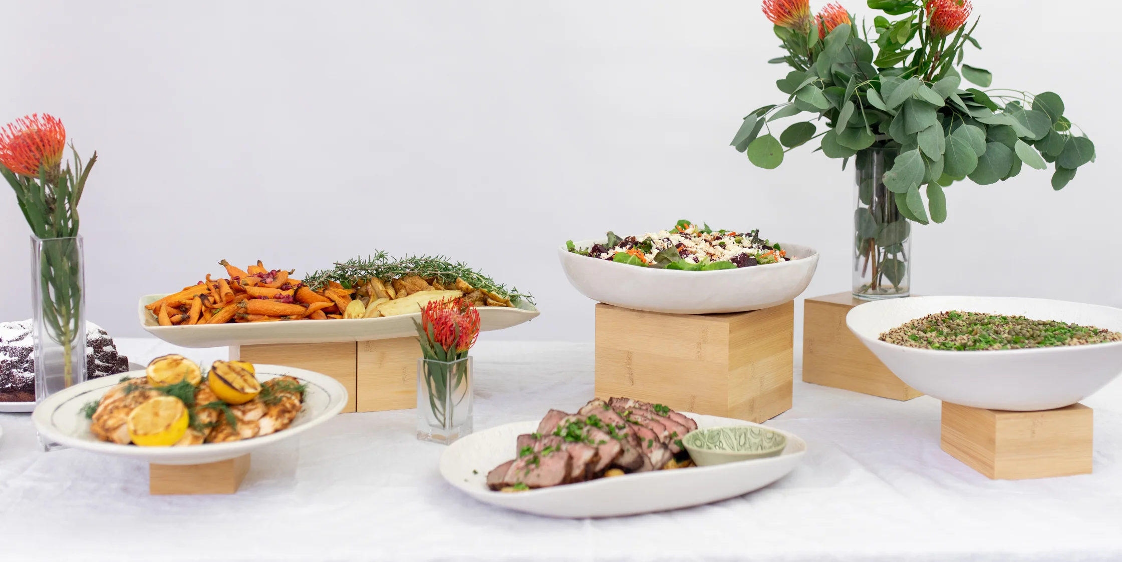 Catered event buffet with Roasted vegetables, salmon, steak, quinoa , salads and cakes